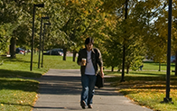 学生端着咖啡走在校园里的人行道上