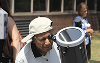 person wearing sideways baseball cap looks through telescope